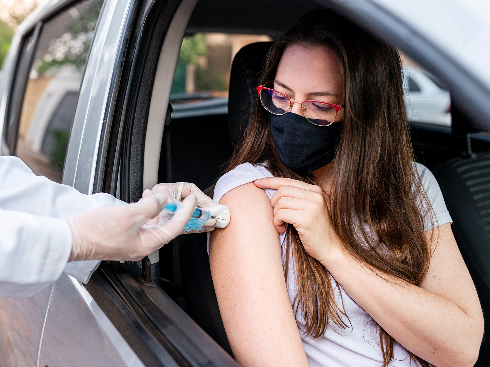 Young woman receives a vaccine from a healthcare professional at a drive-thru clinic