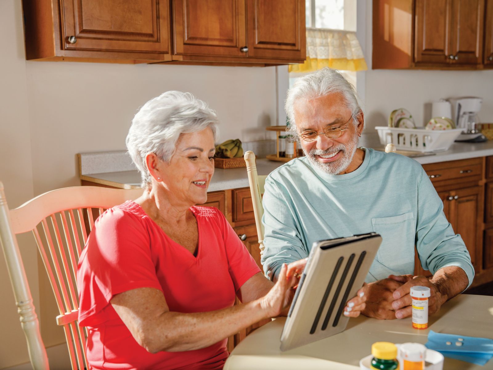 Older man and woman use tablet at table.