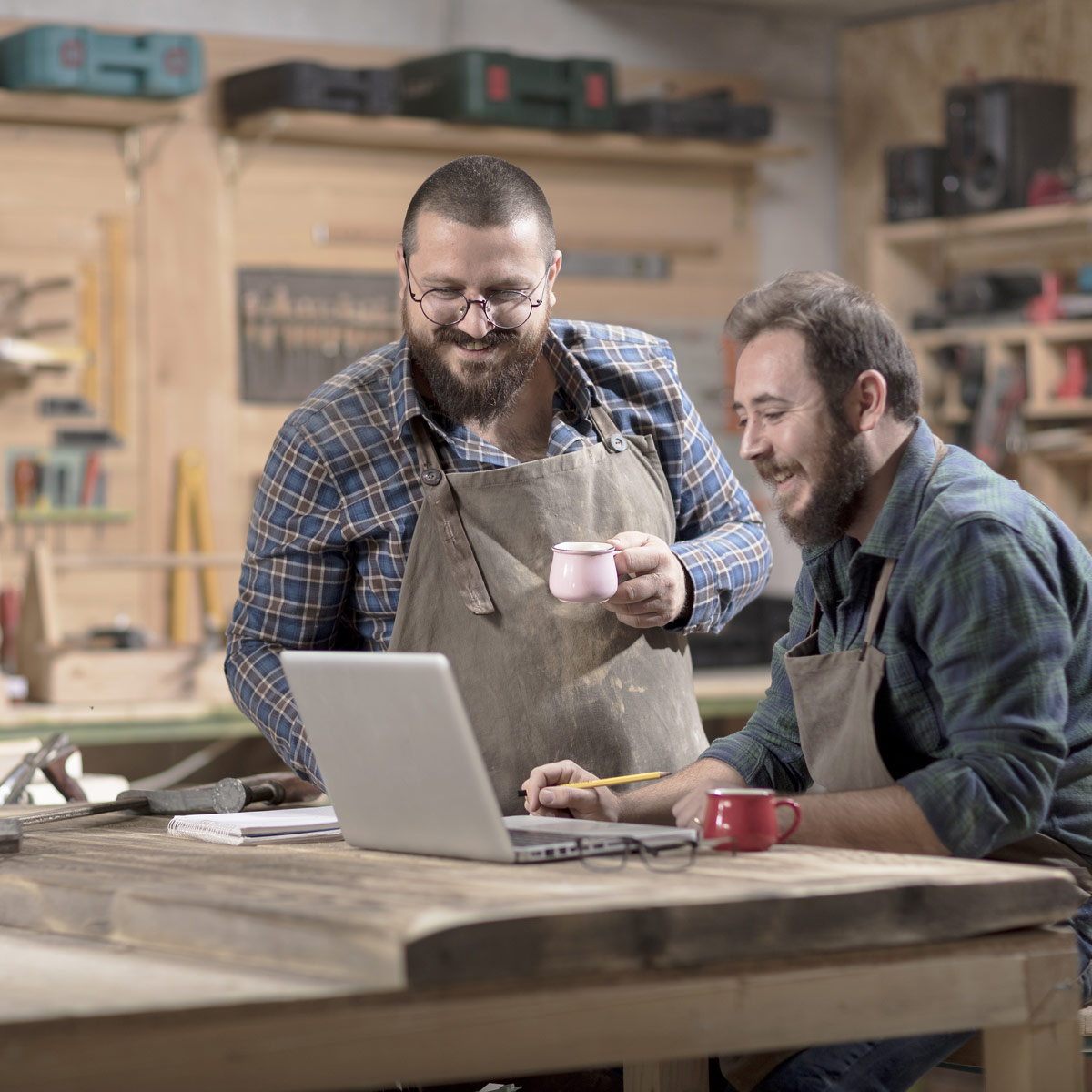 Two employees working on a laptop inside a woodworking design shop