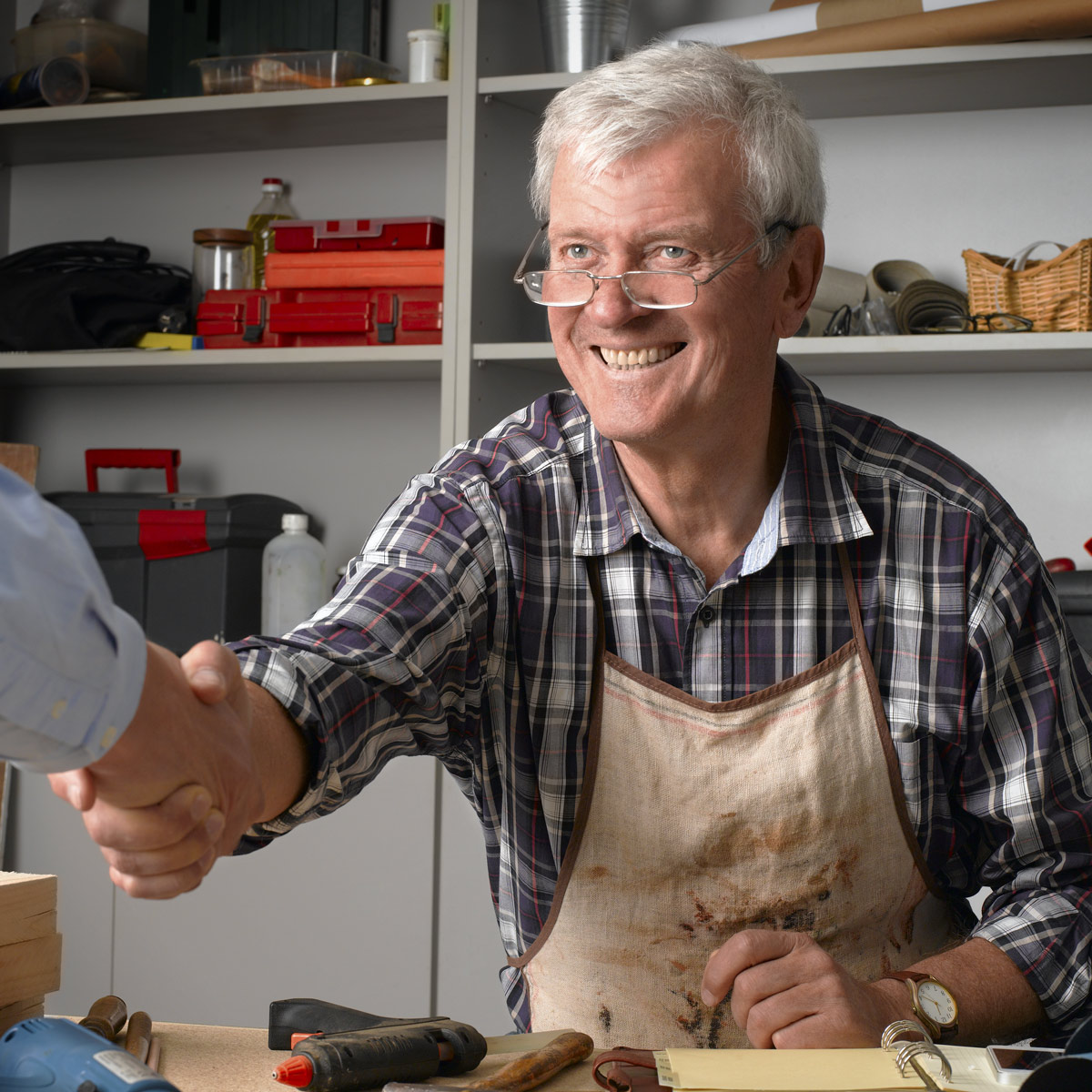 Propietario de negocio dándose la mano con un cliente dentro de su taller de reparación
