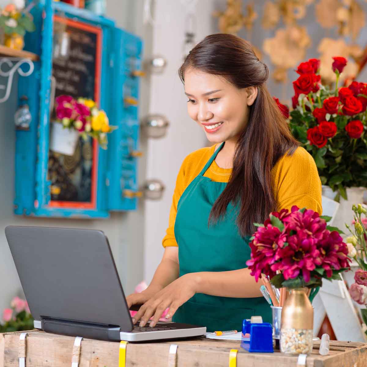 Empresaria frente a una computadora en su tienda de diseño floral