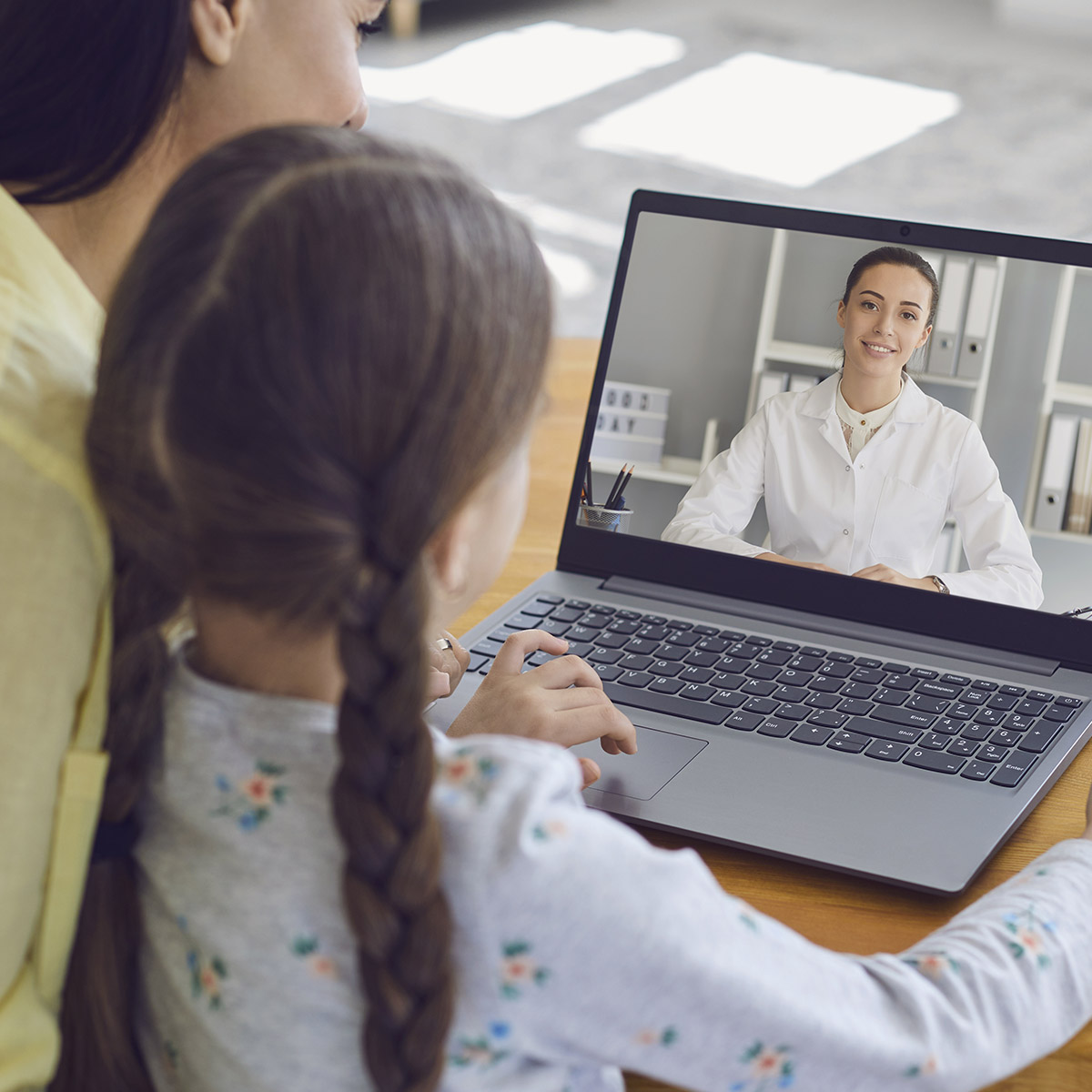 A woman and child video chat with another woman on a laptop.