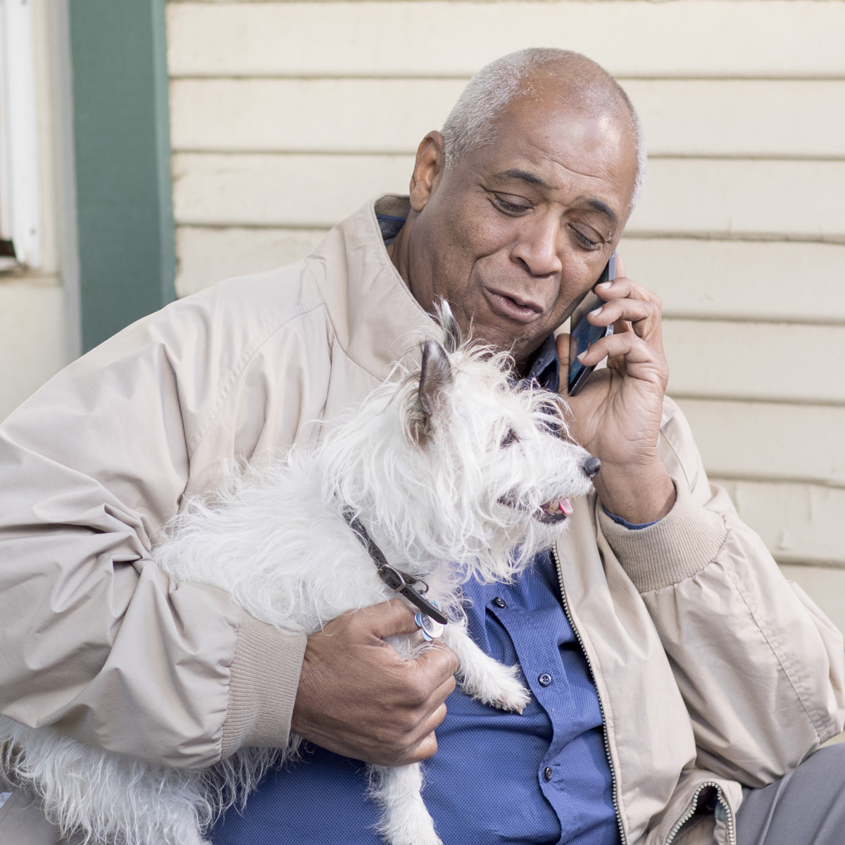 Man on a mobile phone holding a dog