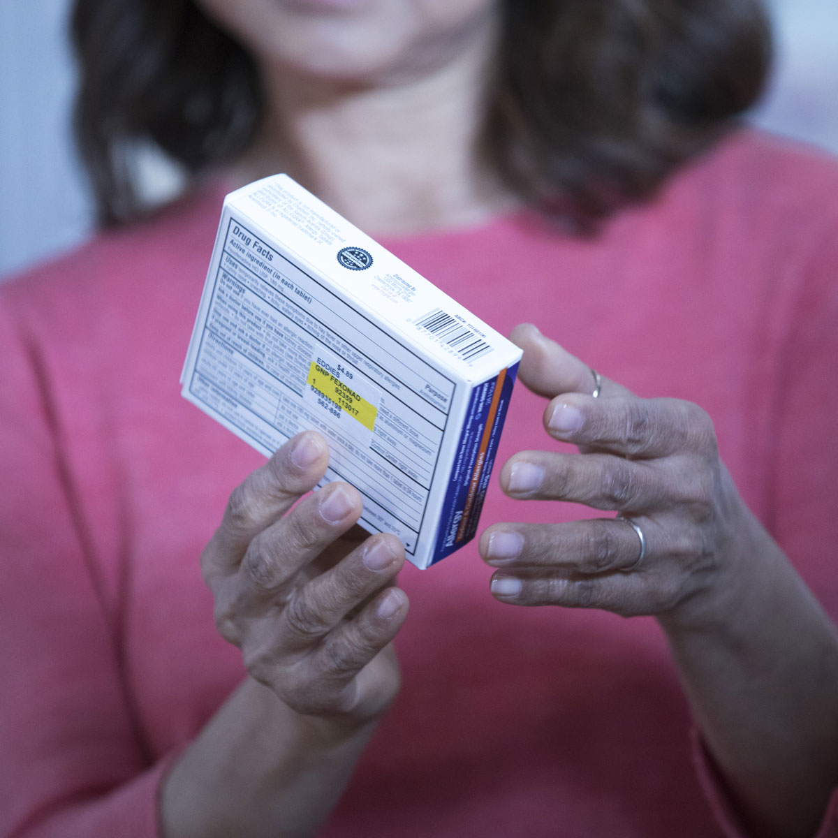 A close up image of a woman holding an over-the-counter medication.