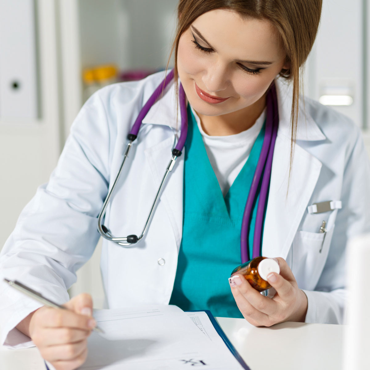 Una médica con una botella recetada escribiendo notas en un expediente clínico.