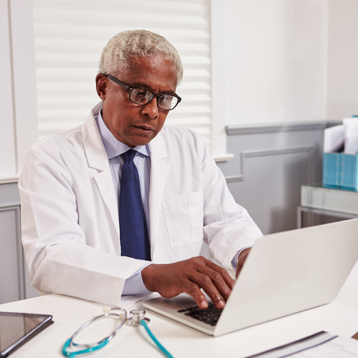 médico trabajando en un computador portátil en su consultorio