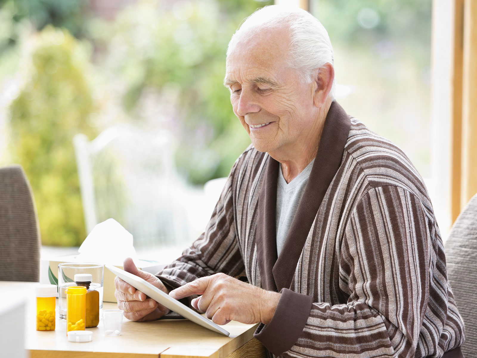 Man sitting at dining table reviewing his prescriptions and prescription documents in front of him