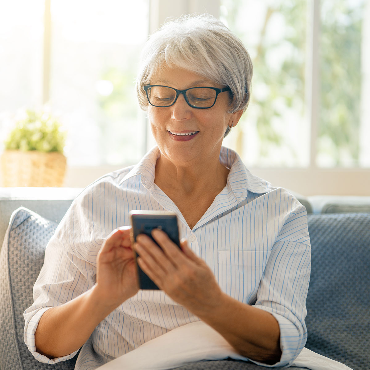 Una mujer sonríe mientras usa una aplicación en su smartphone.
