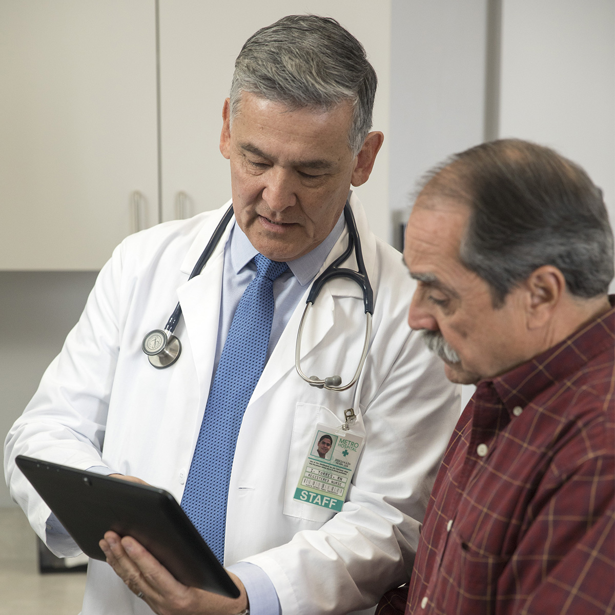 Male doctor showing information on electronic device to male patient