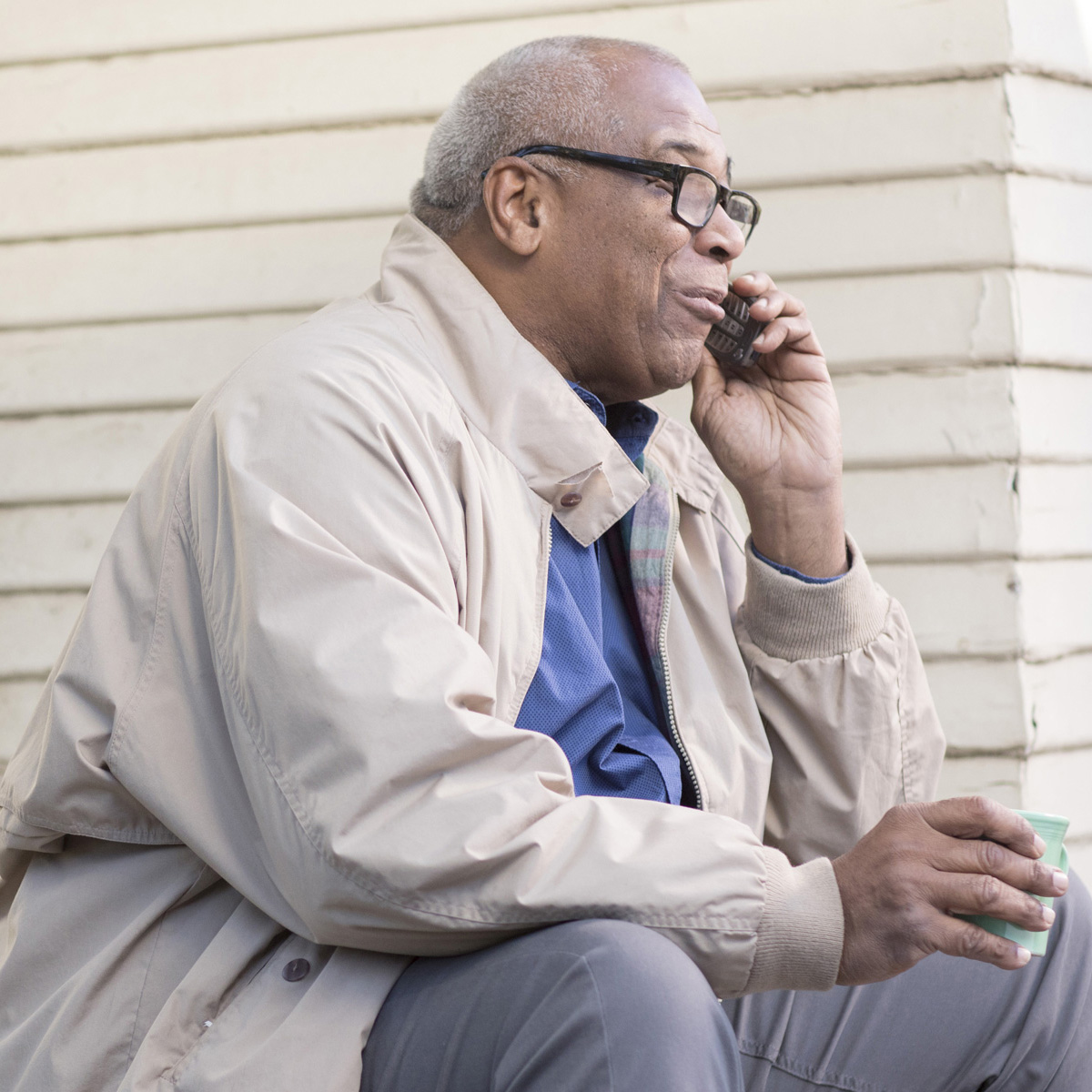 Senior man sitting on porch steps with mobile phone