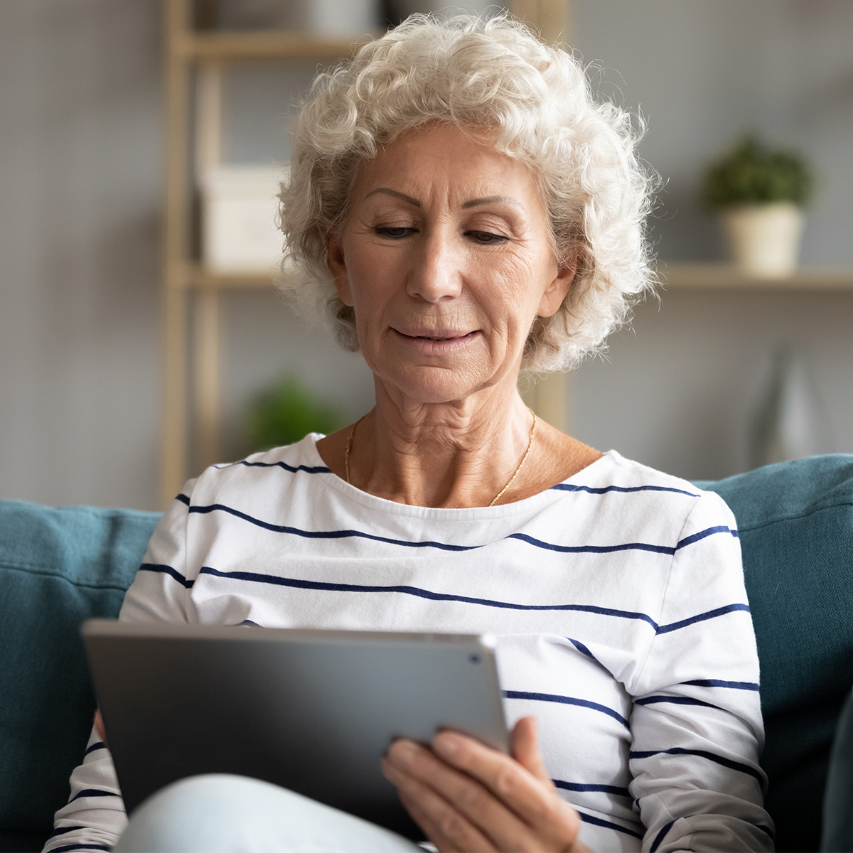 woman sits on couch reading her tablet