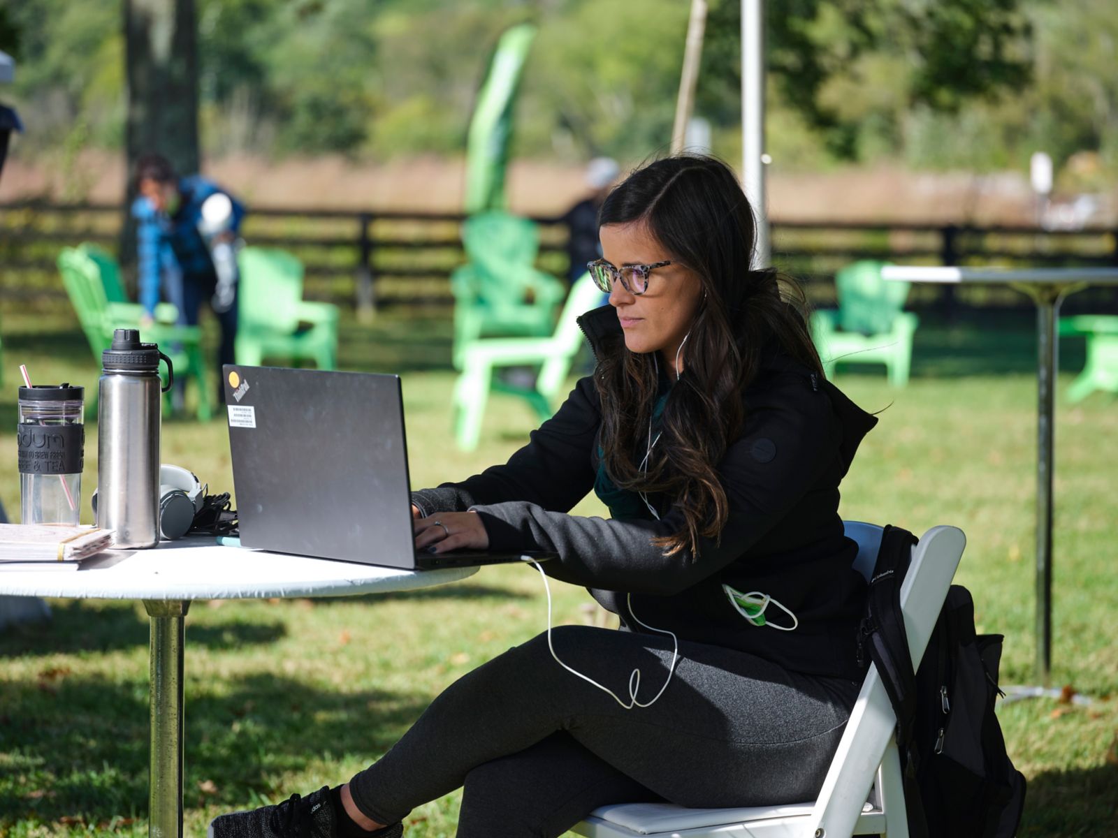 Una mujer sentada al aire libre trabajando con su computador
