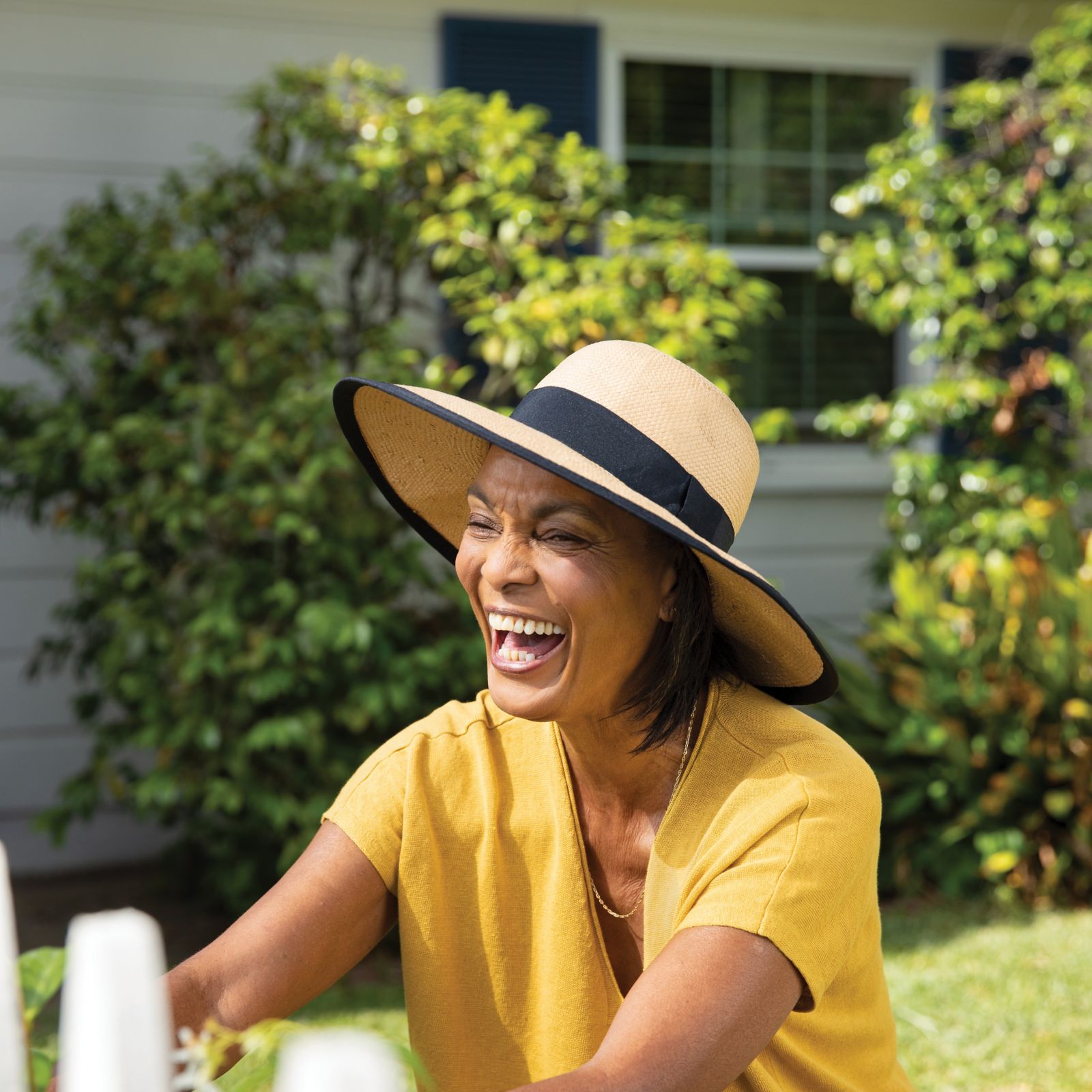 Una mujer sentada afuera con un sombrero para el sol puesto