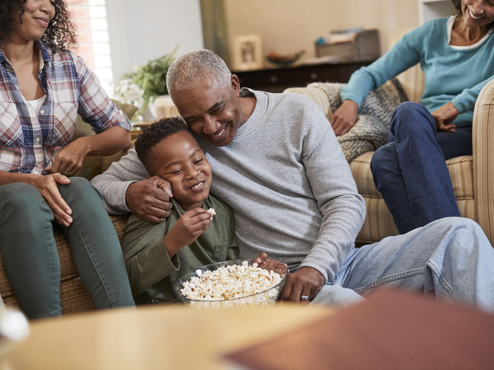 A family enjoys eating popcorn and spending time together in the living room.