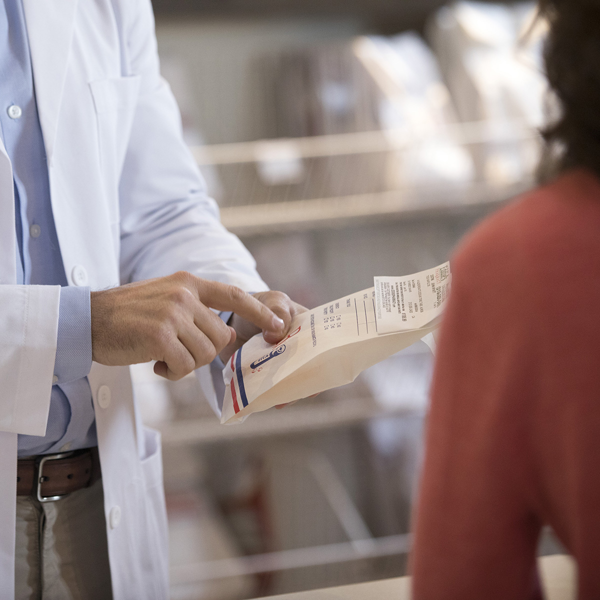 A close up on a pharmacist holding a prescription pointing at the directions.