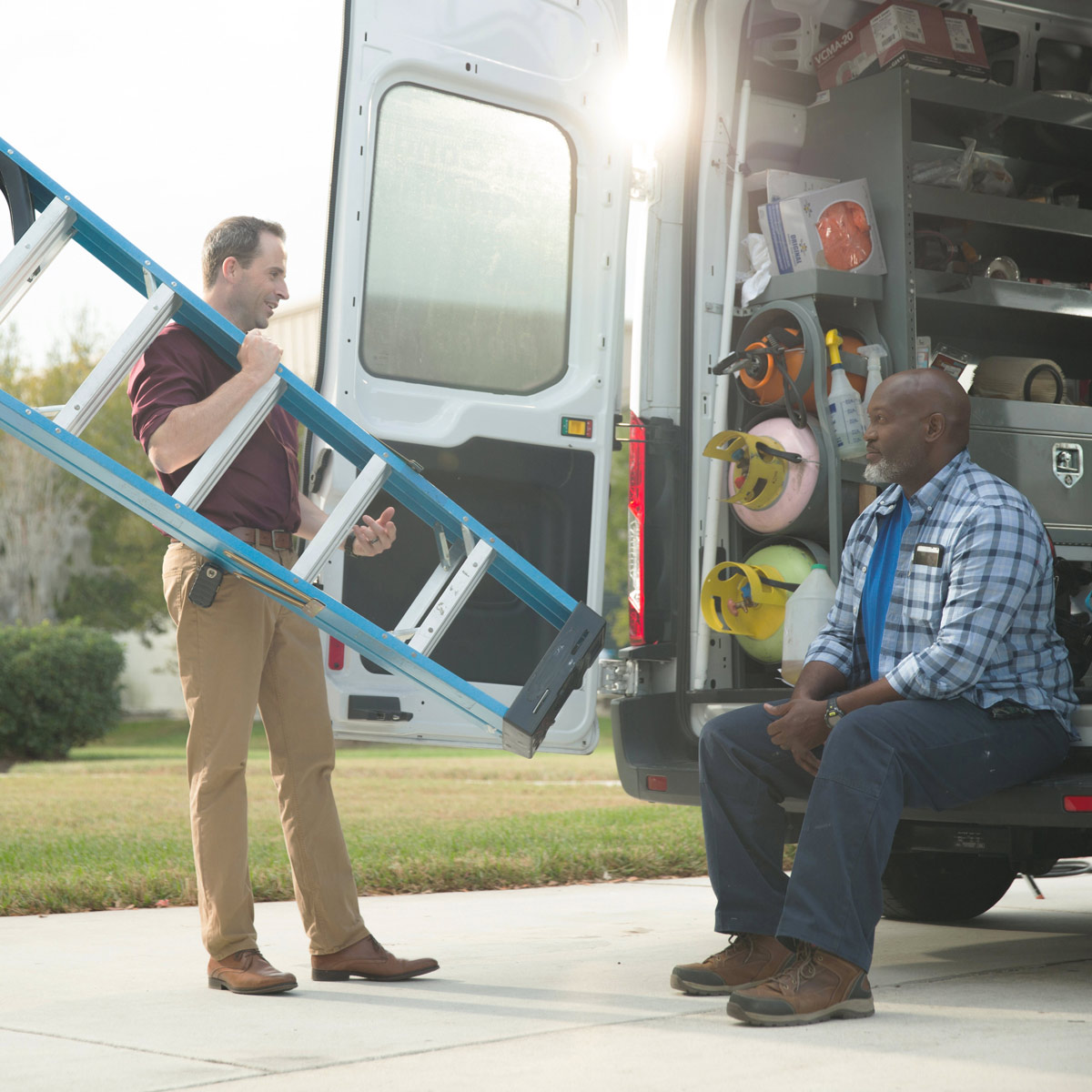 Man with a ladder speaking with man in a van
