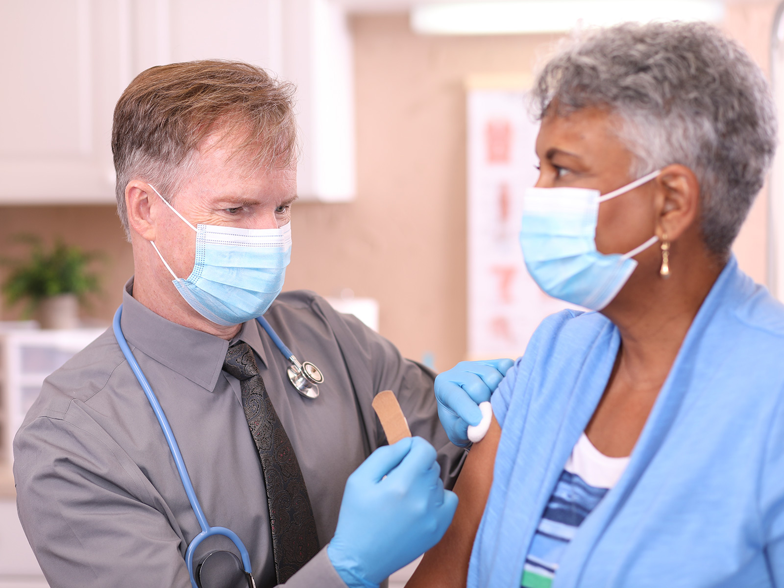 Una mujer mayor afroamericana recibe la vacuna de un profesional de atención de la salud.