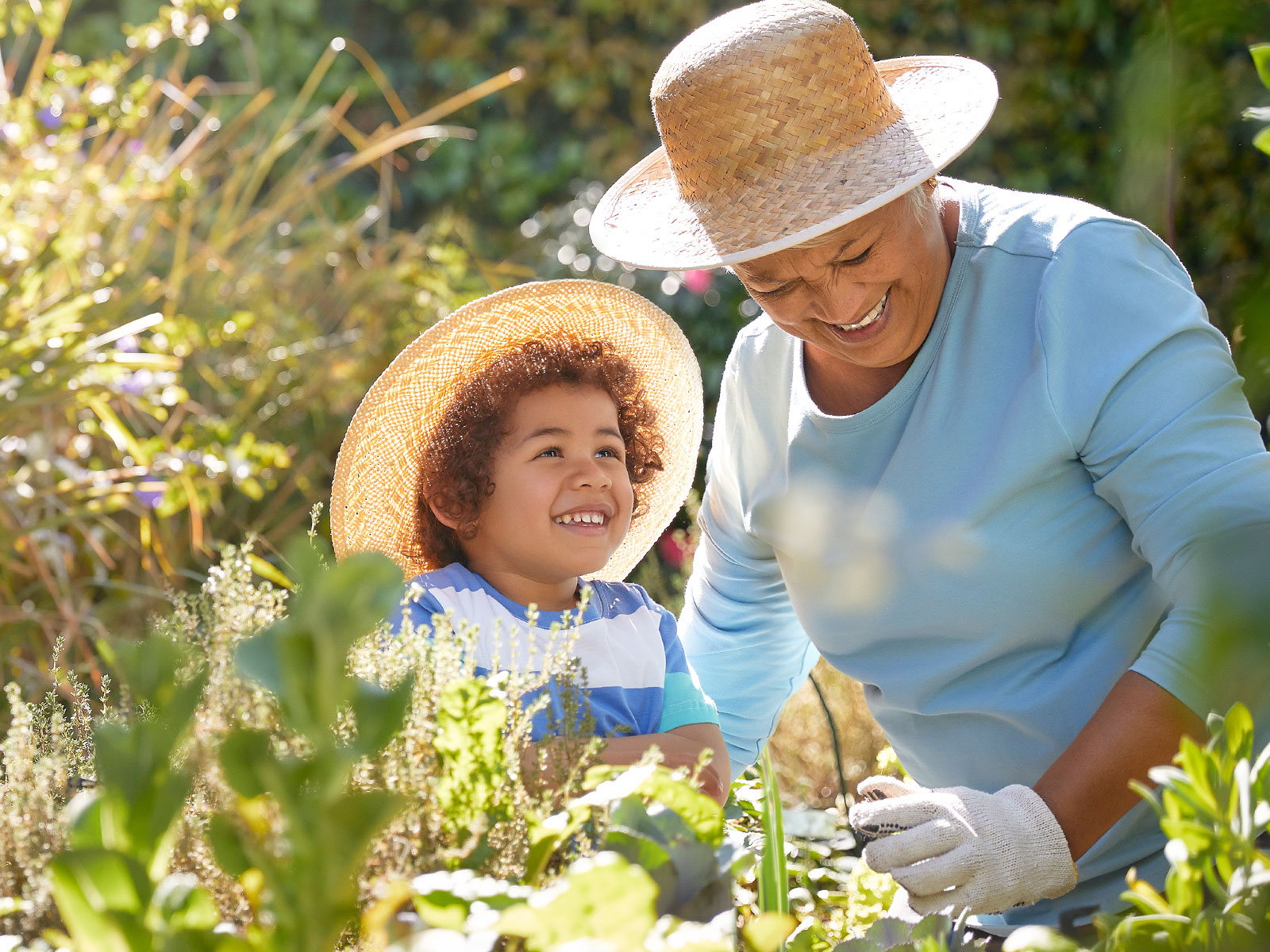 Una abuela trabajando en el jardín junto a su nieto