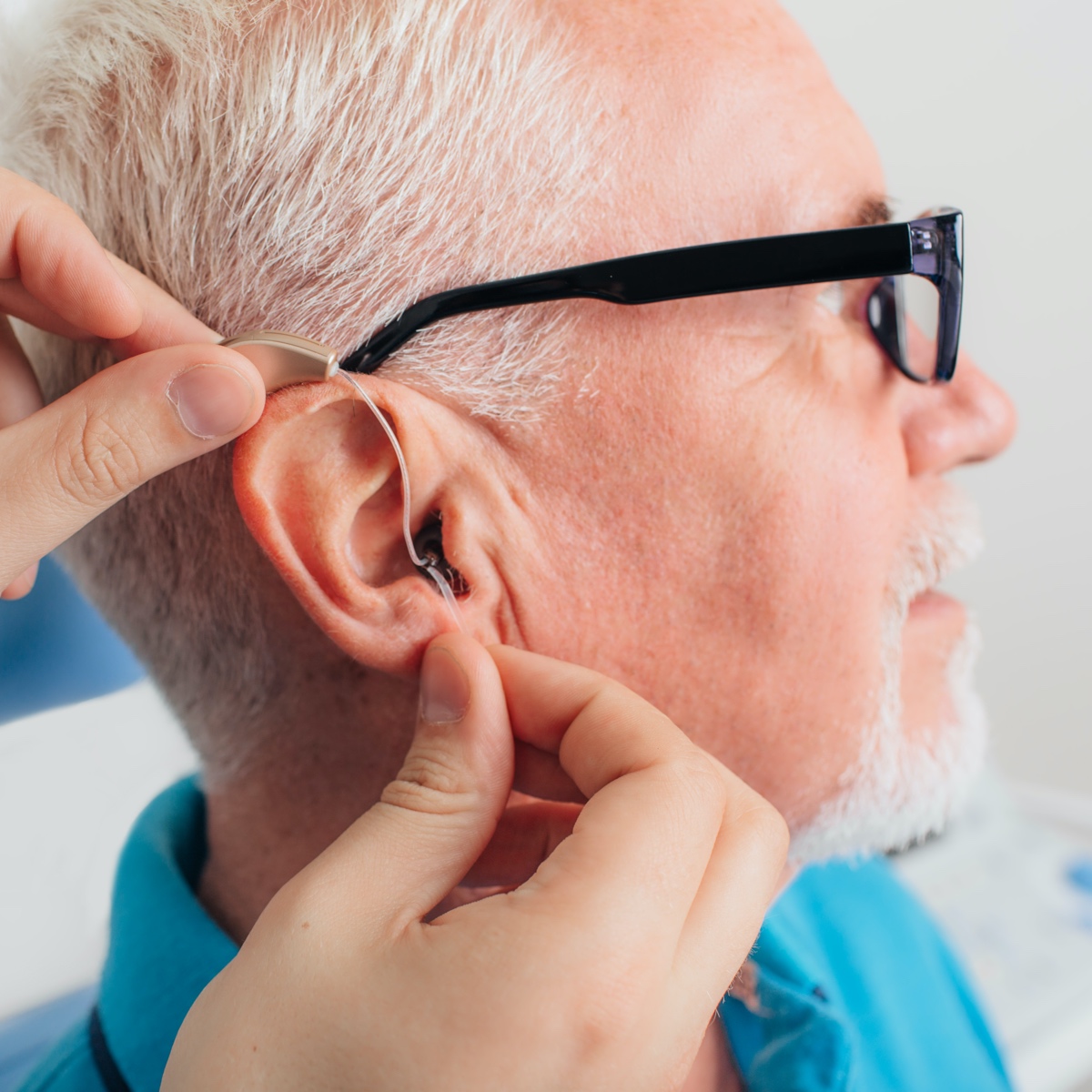 Senior man putting in hearing aids.