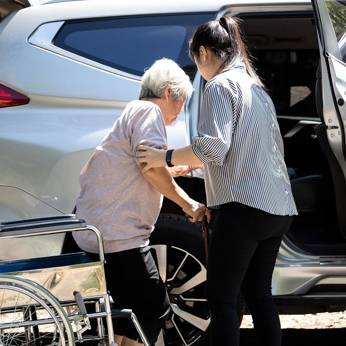 Un cuidador ayuda a una mujer a entrar en su auto