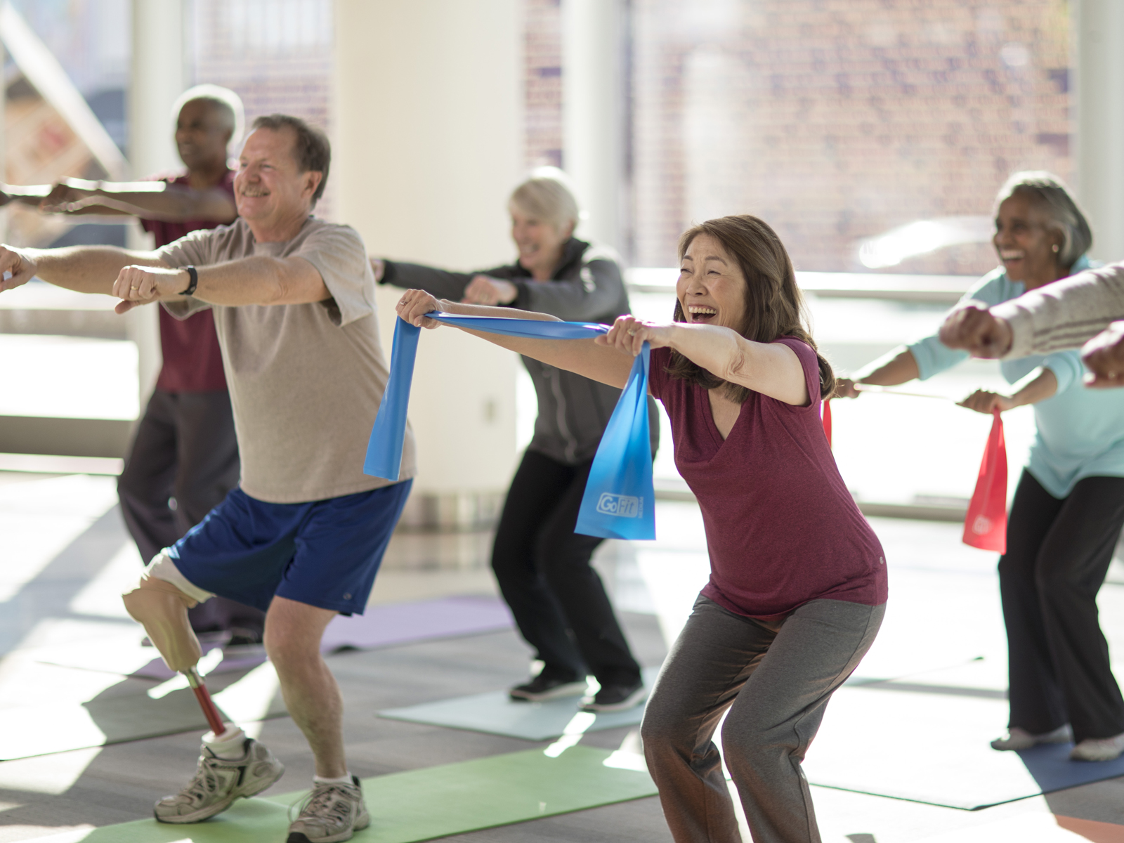Un grupo diverso de personas mayores participando de una clase de ejercicios.