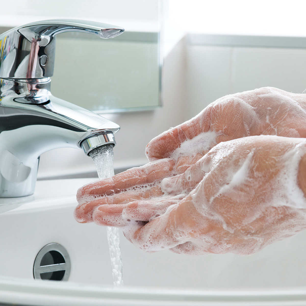 Person vigorously washing hands in sink