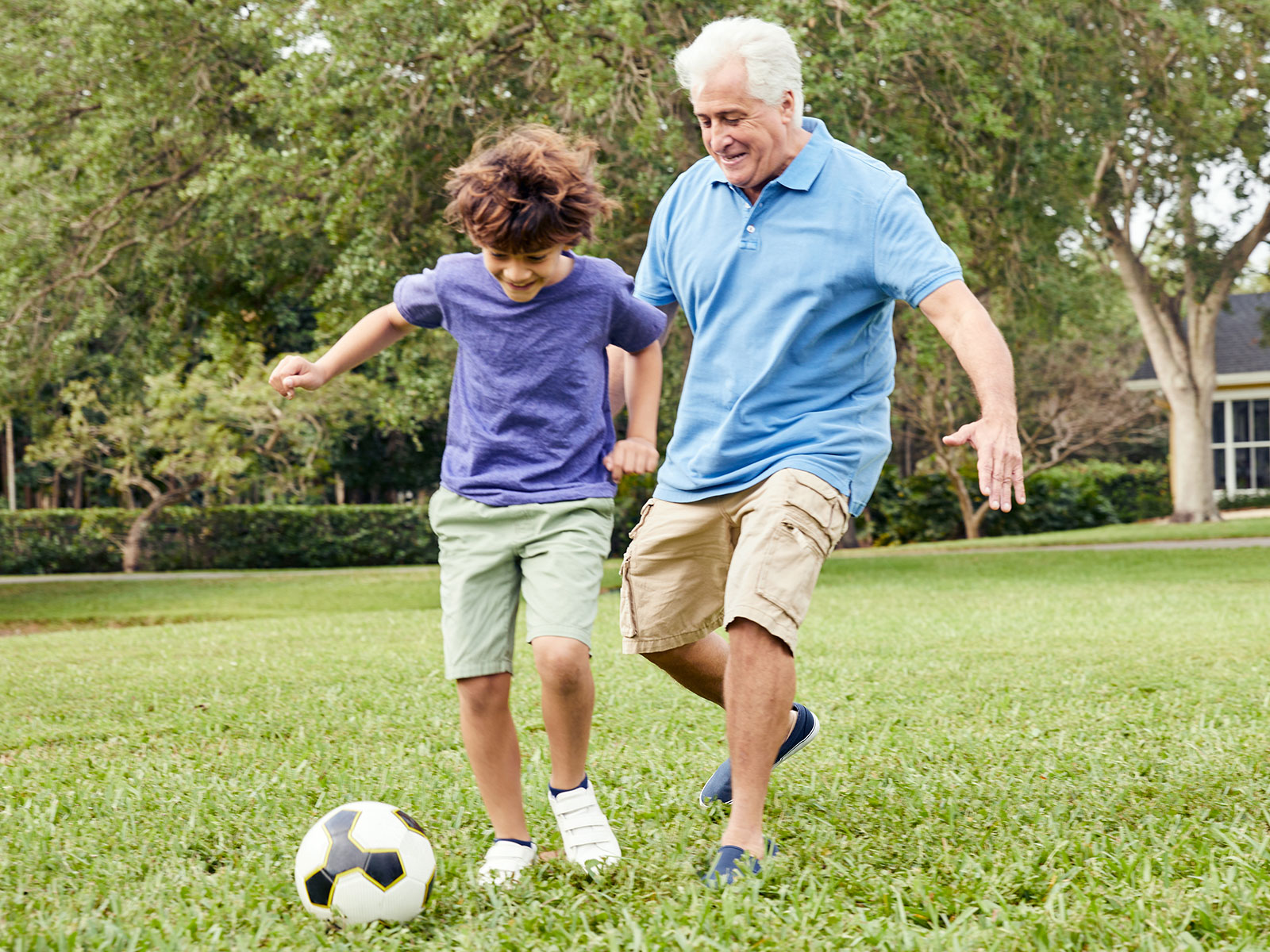 Grandfather plays soccer with grandson.