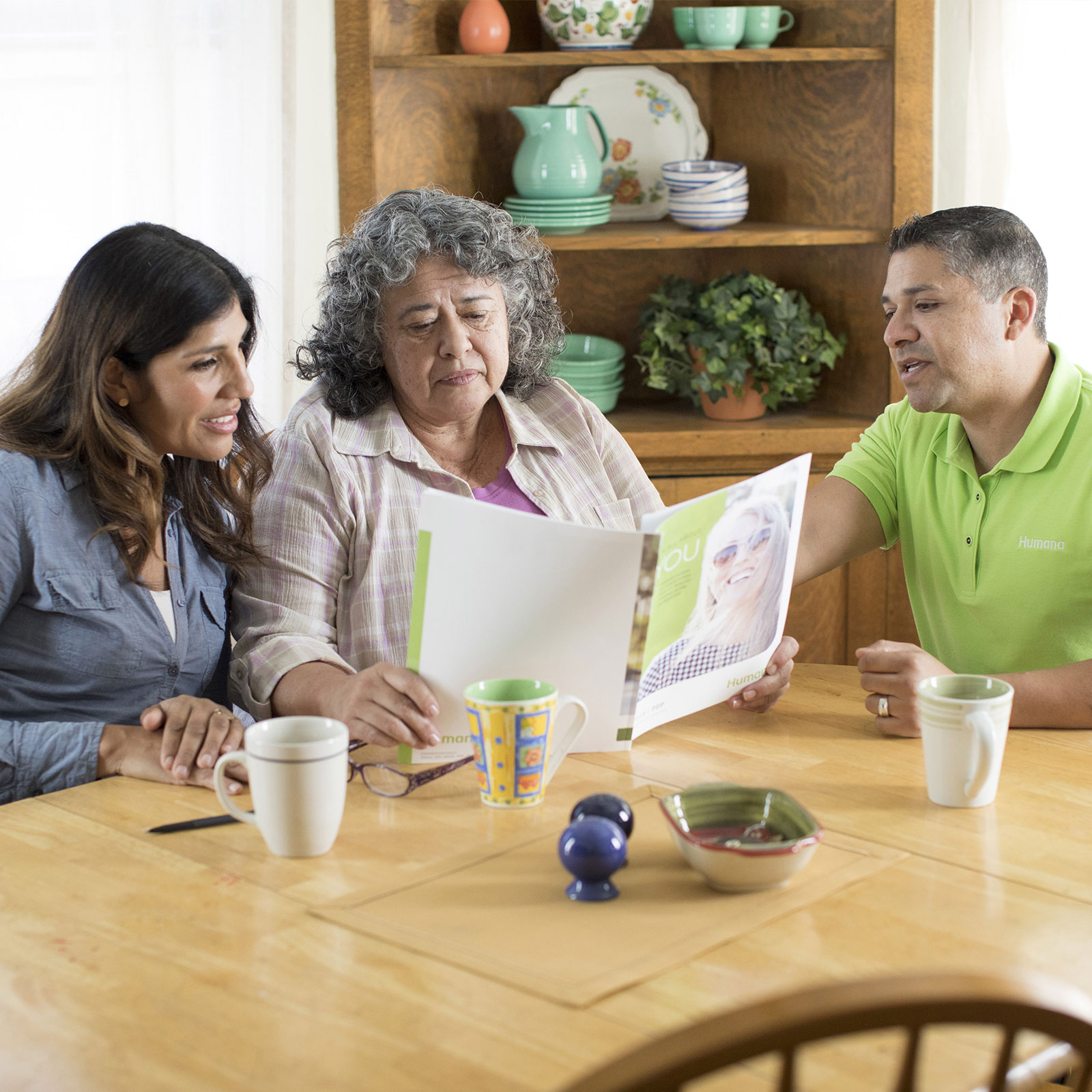 A Humana agent consults a family while they read a pamphlet.