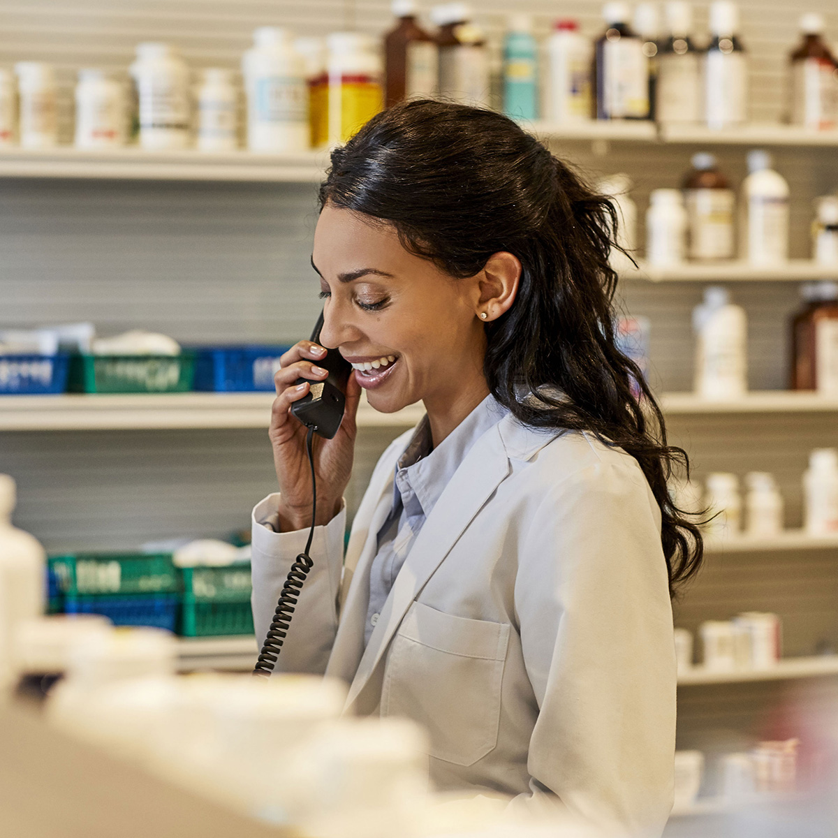 Pharmacist smiling while she talks on the phone.
