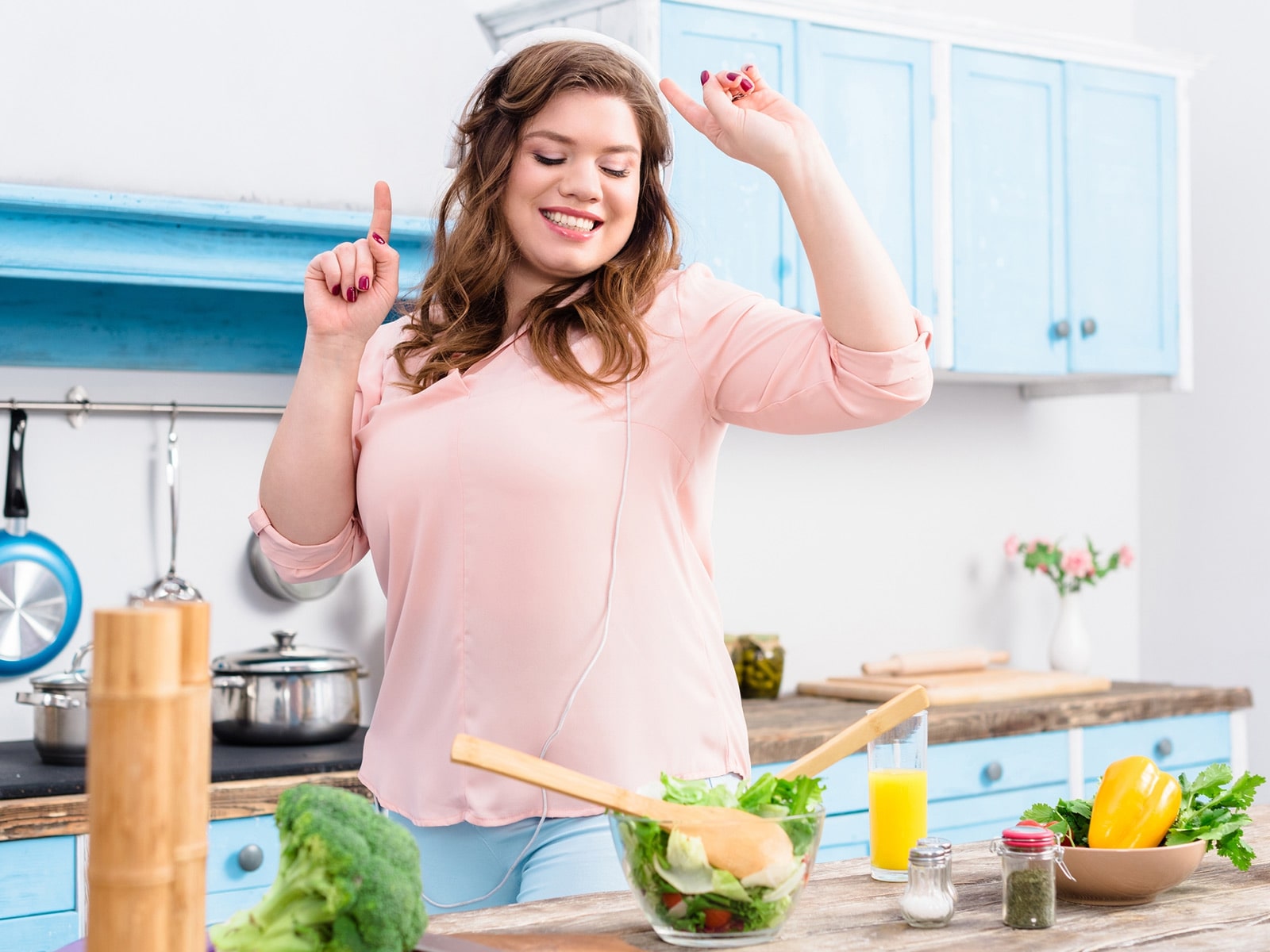 Mujer baila feliz mientras cocina una comida saludable.