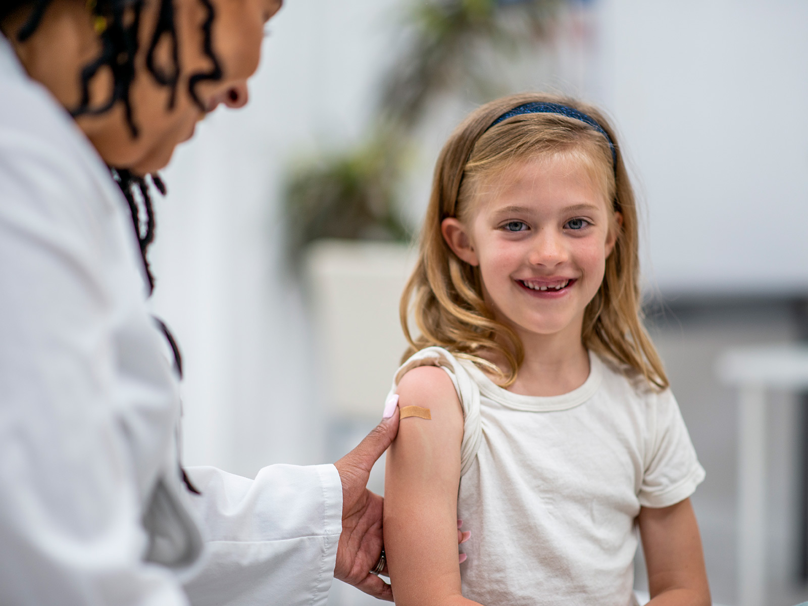 Healthcare provider places bandaid on smiling girl after flu shot.