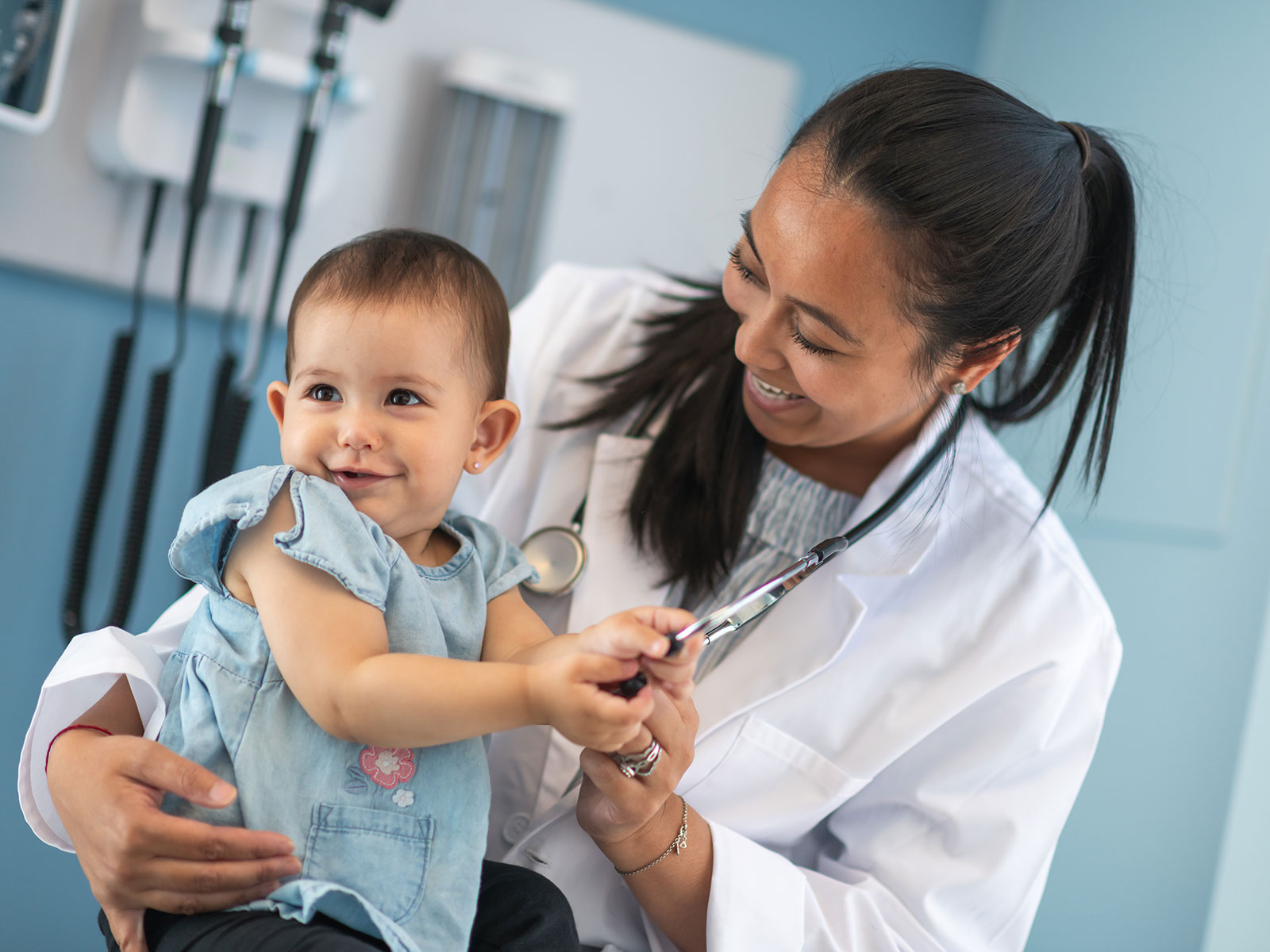 Proveedora de servicios de salud sostiene en brazos a un bebé durante un chequeo médico de rutina