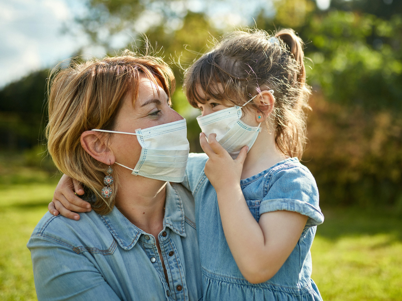 Mother and daughter wearing masks outside in a field.