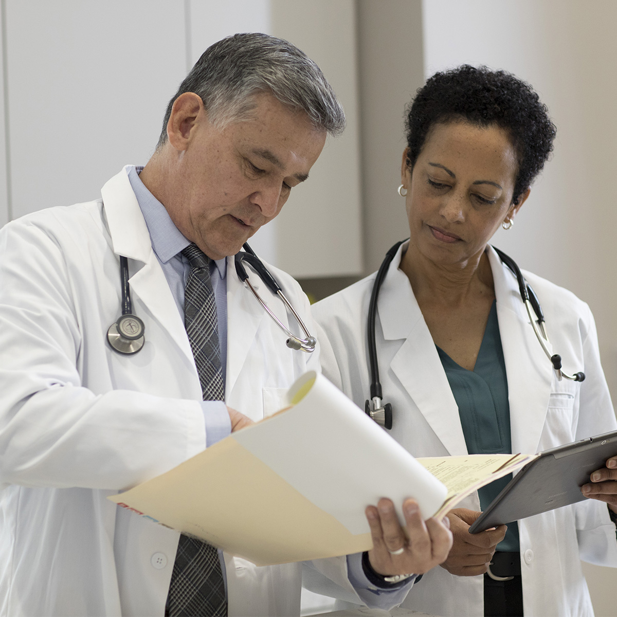 Two doctors side by side reviewing files.