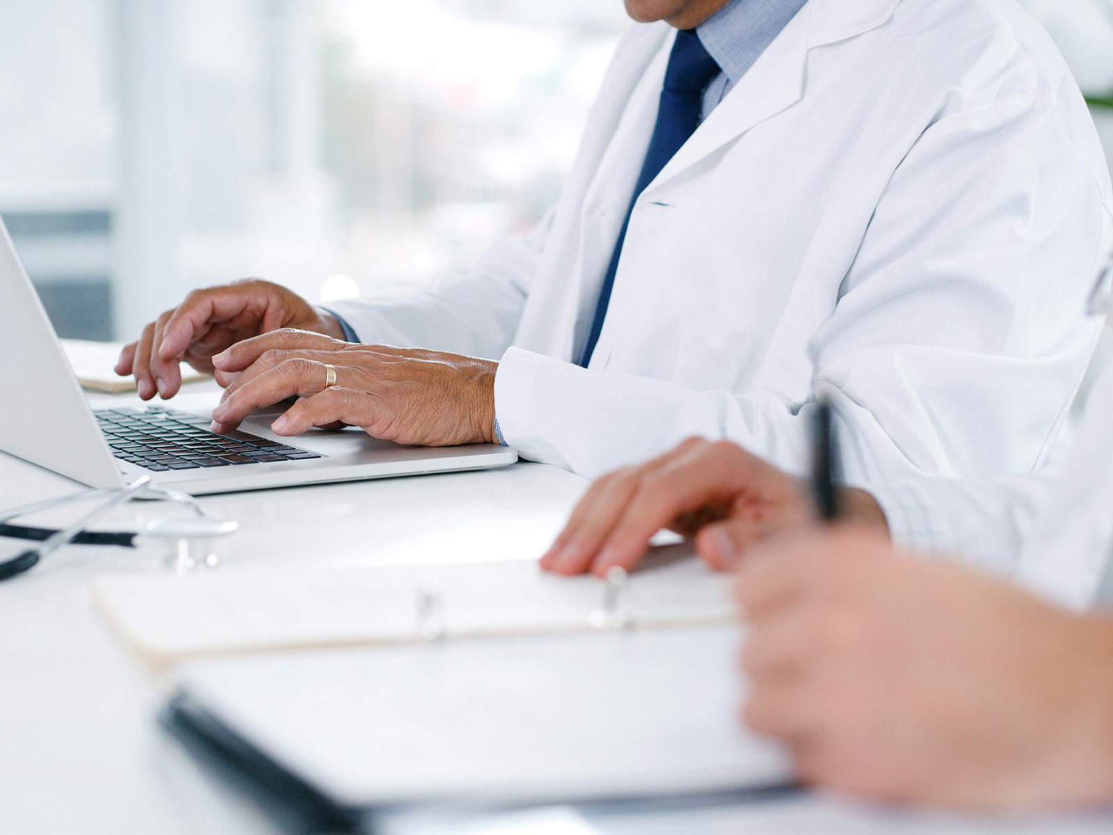 Médicos tipeando y revisando papeles de Medicaid