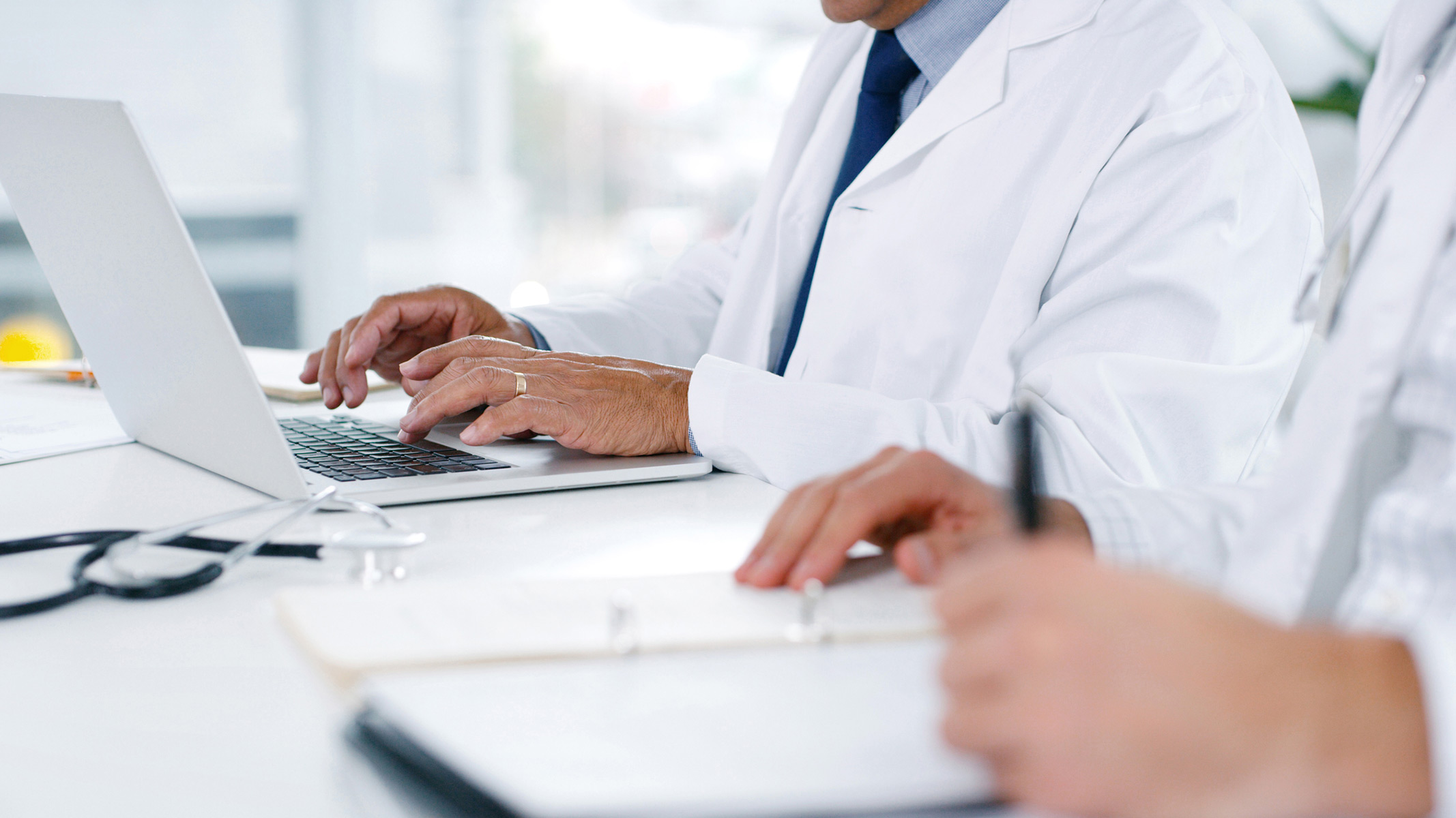 Doctors typing and reviewing Medicaid paperwork