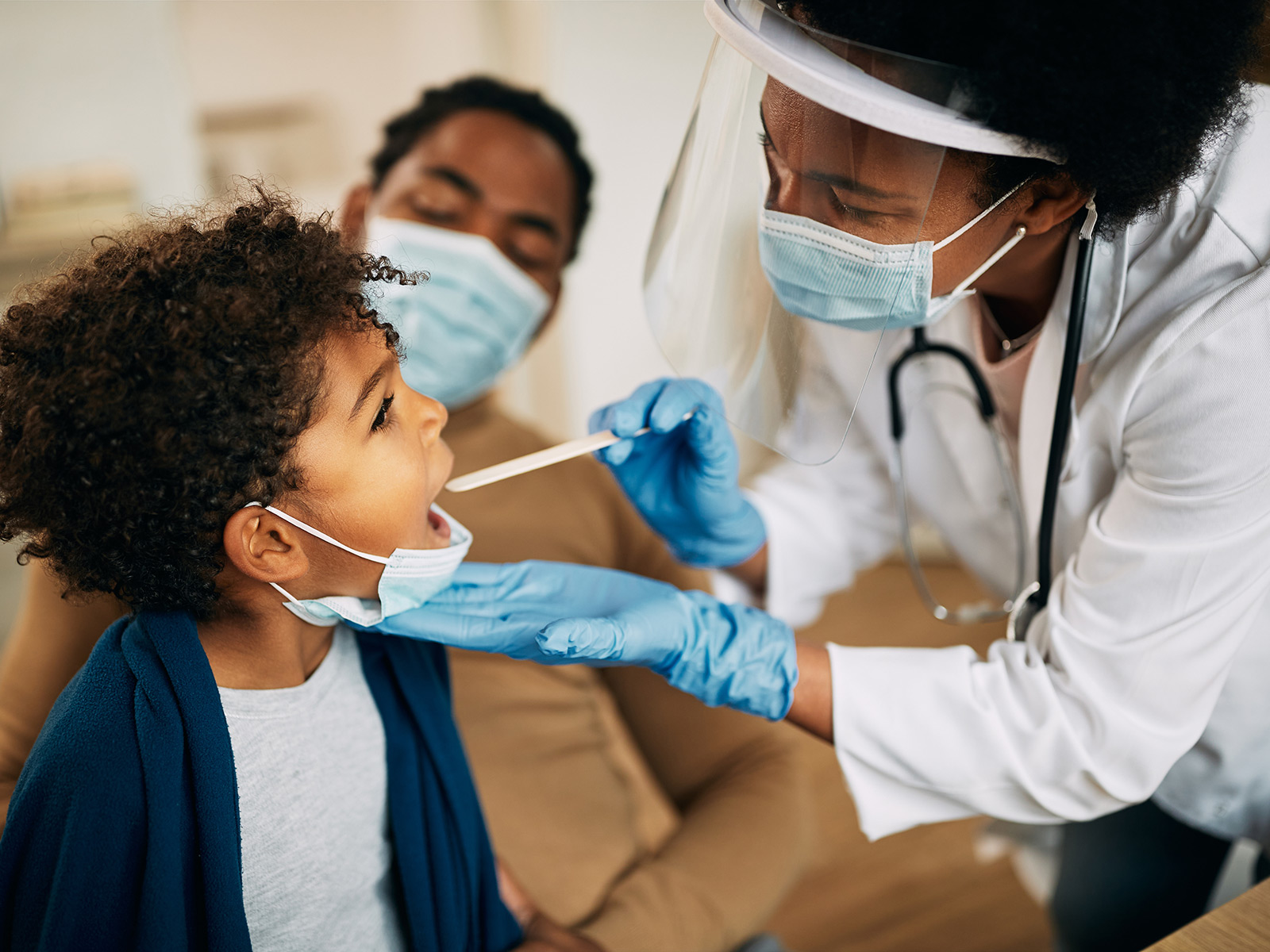 Médico familiar examinando la garganta de un niño/afiliado de Medicaid
