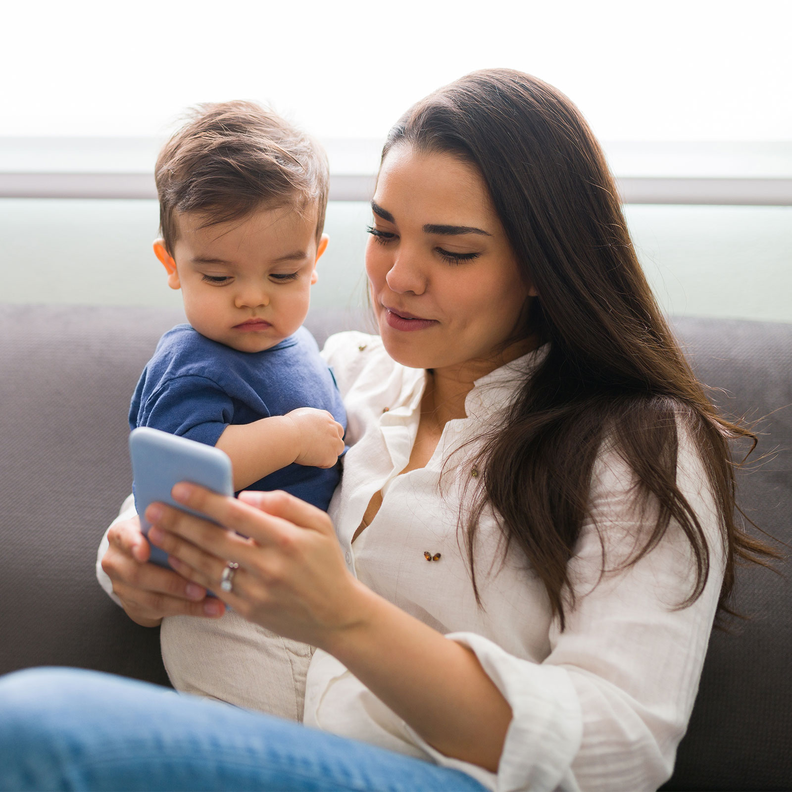young mother holding child and looking at phone
