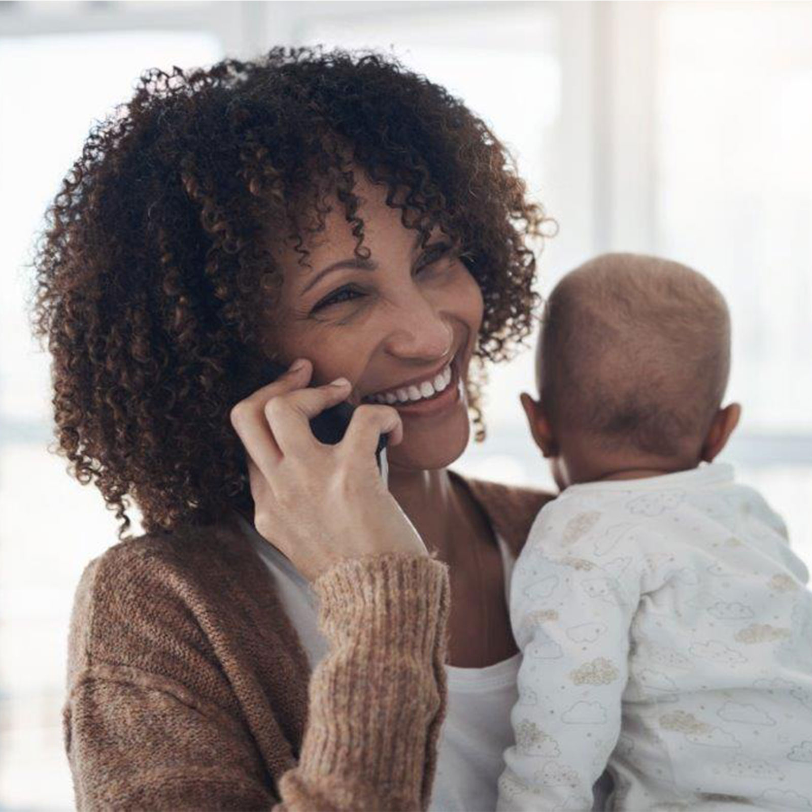 Afiliada de Medicaid sosteniendo un bebé y hablando por teléfono.