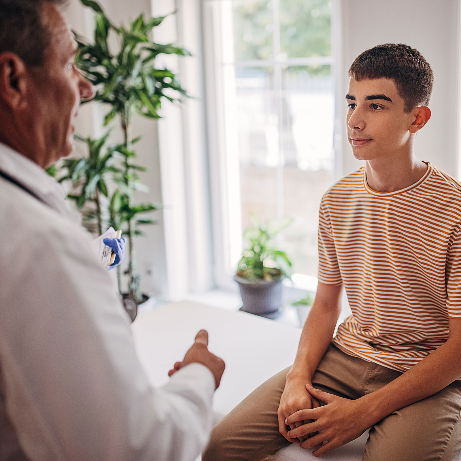 Doctor speaking to young male patient in exam room