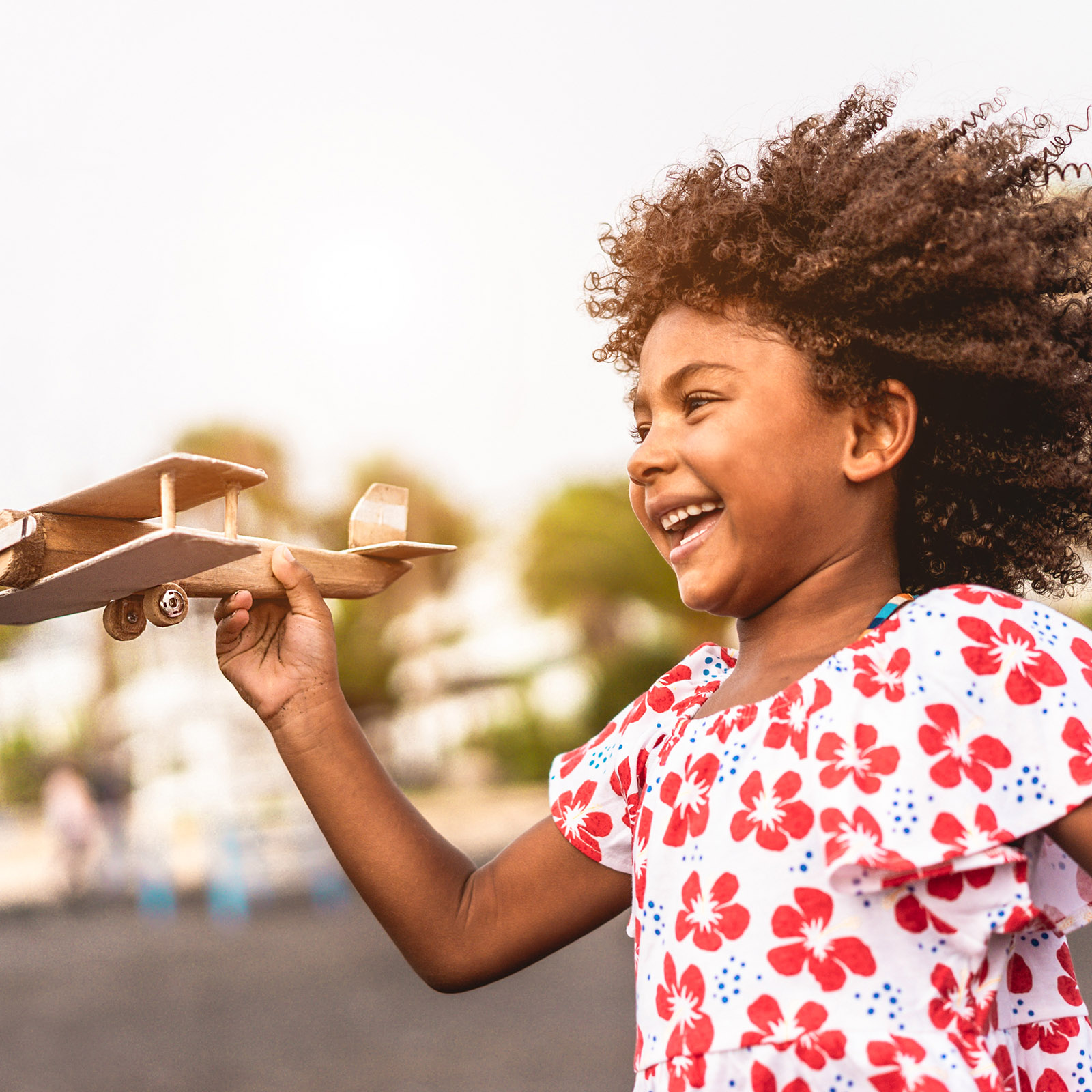 Young girl plays outside with a toy airplane