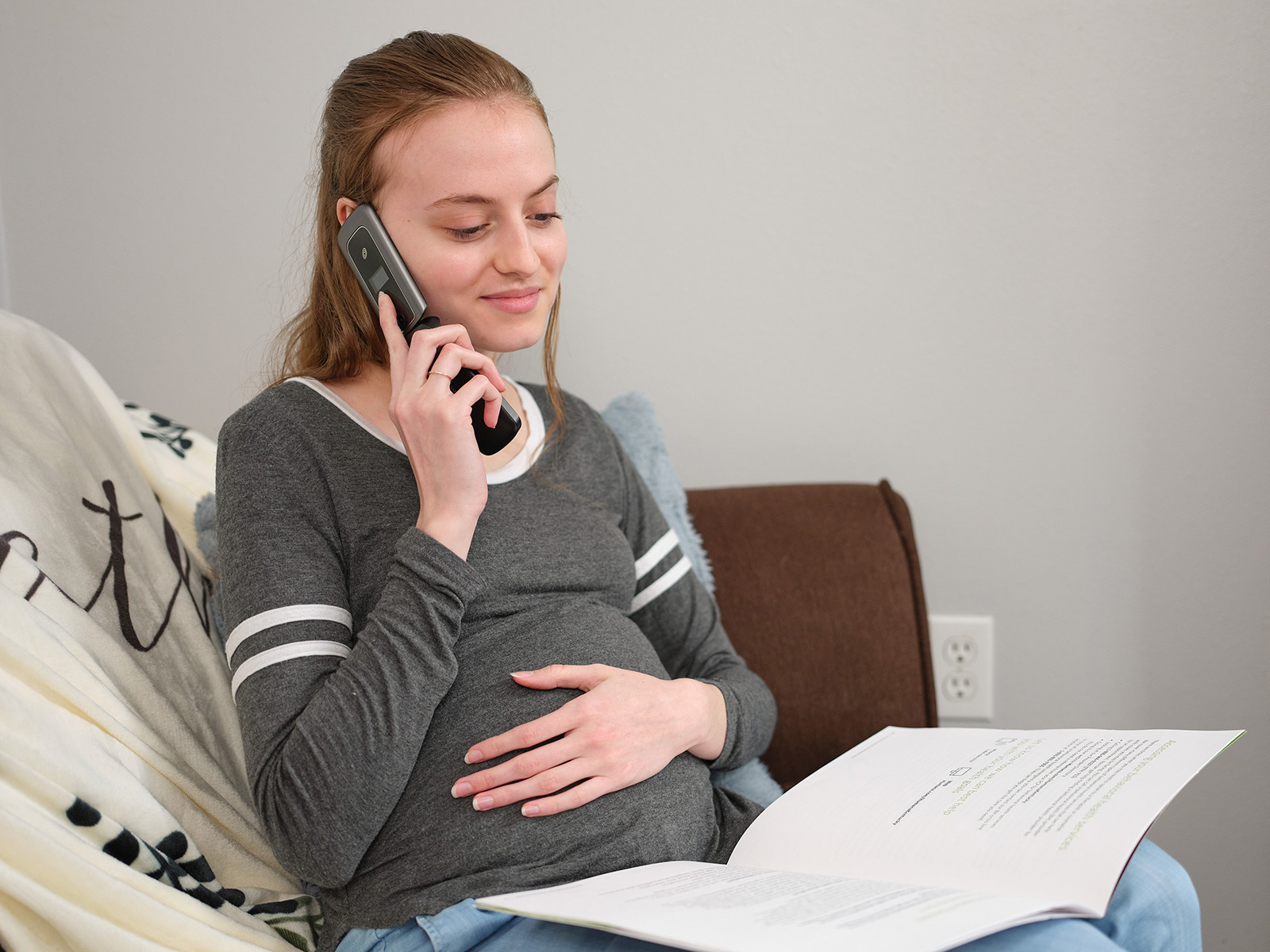 Joven afiliada de Medicaid embarazada hablando por teléfono
