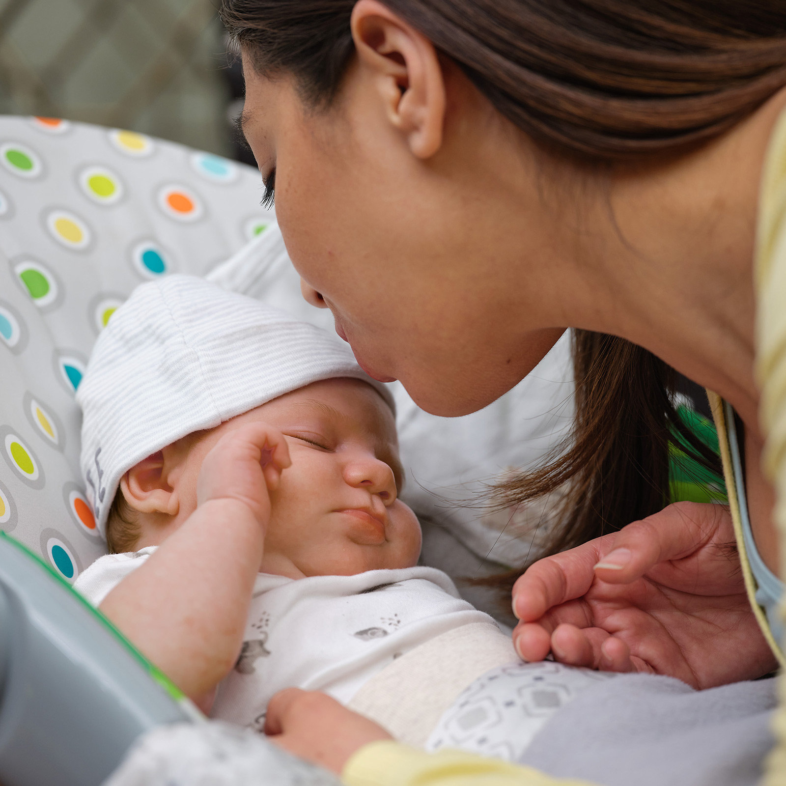 Una mamá primeriza besa a su hijo recién nacido en su cochecito