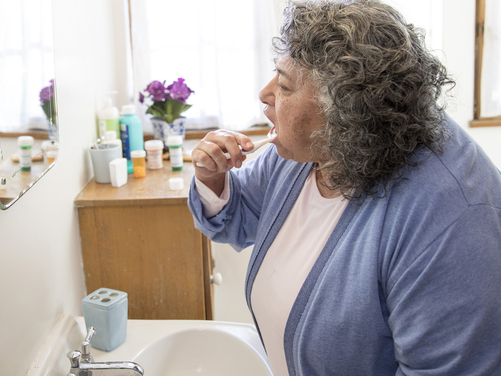 A woman brushes her teeth in the bathroom.