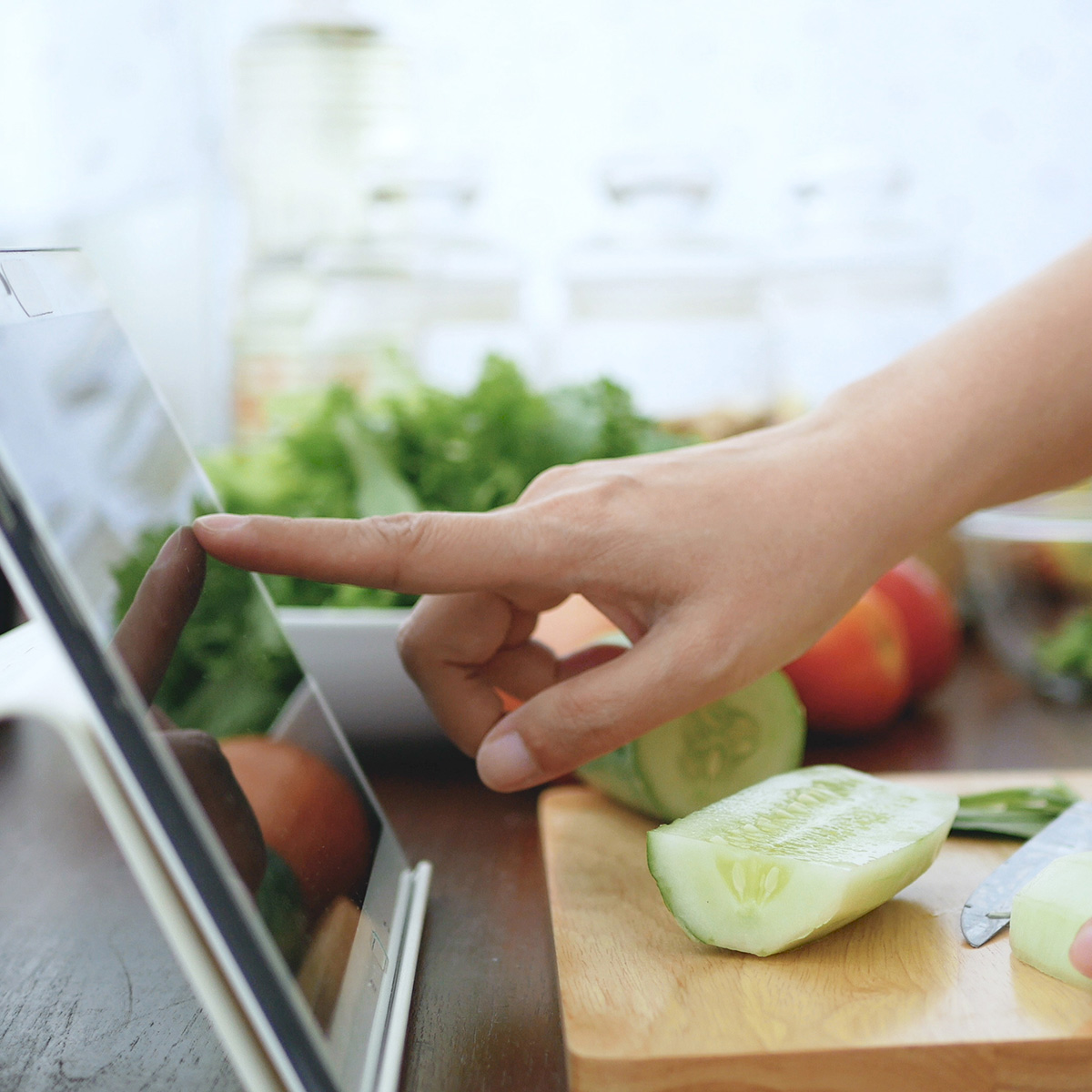 Woman cooking a recipe in her kitchen by following instructions on her tablet
