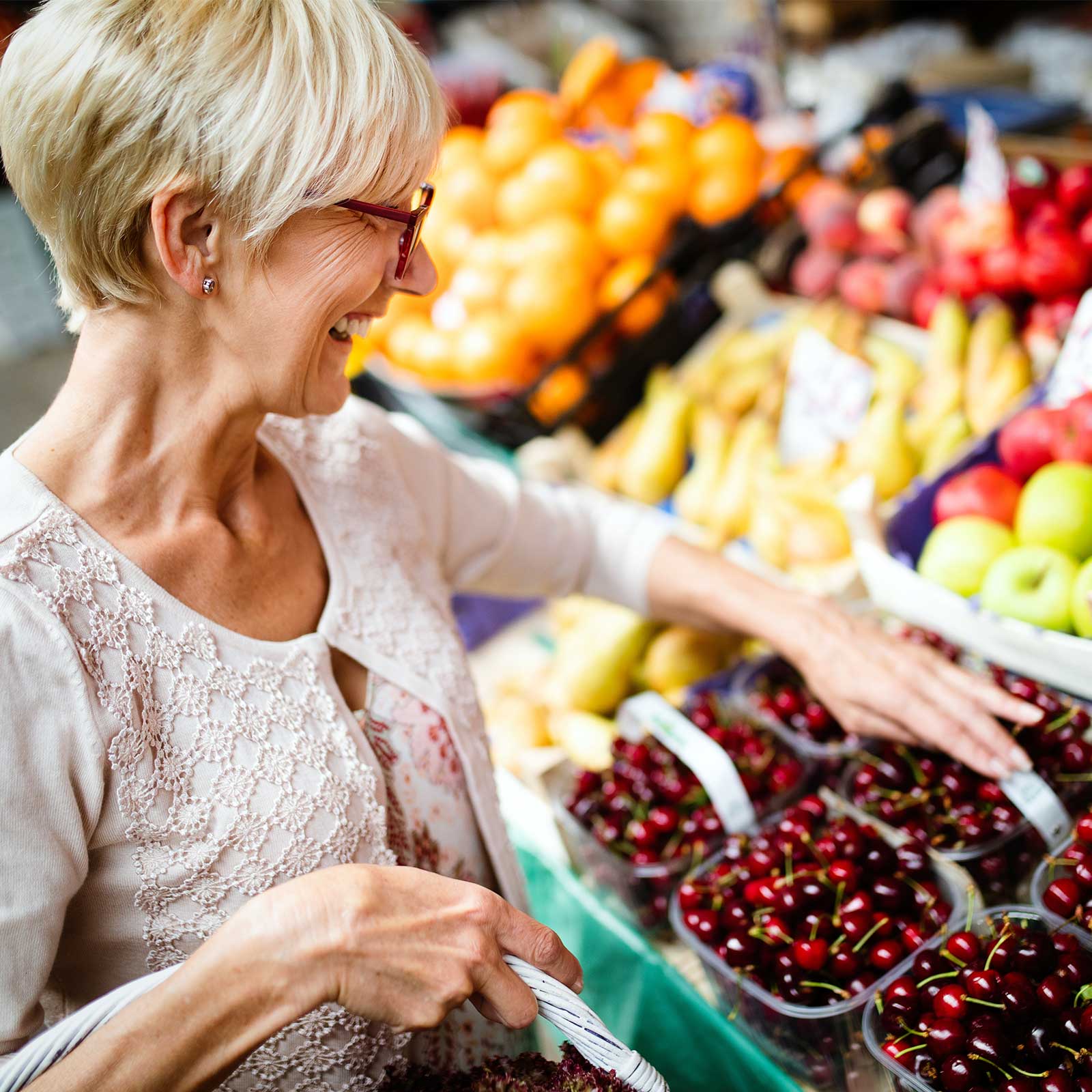 Older woman shops for fresh fruit in grocery store.